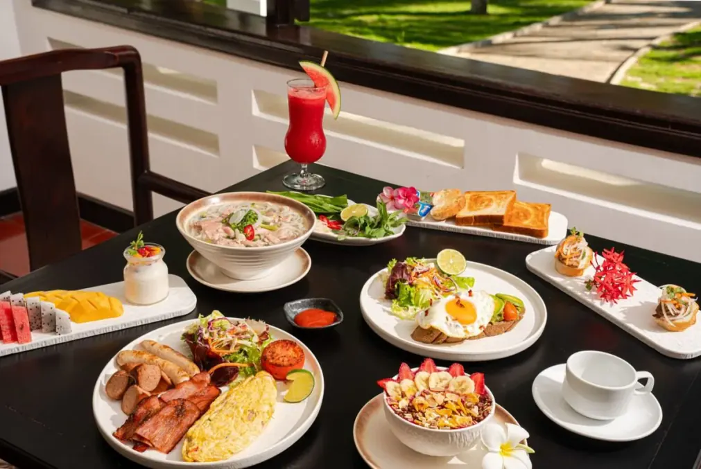 Breakfast laid out in the restaurant: Vietnamese and western plates on the dark table