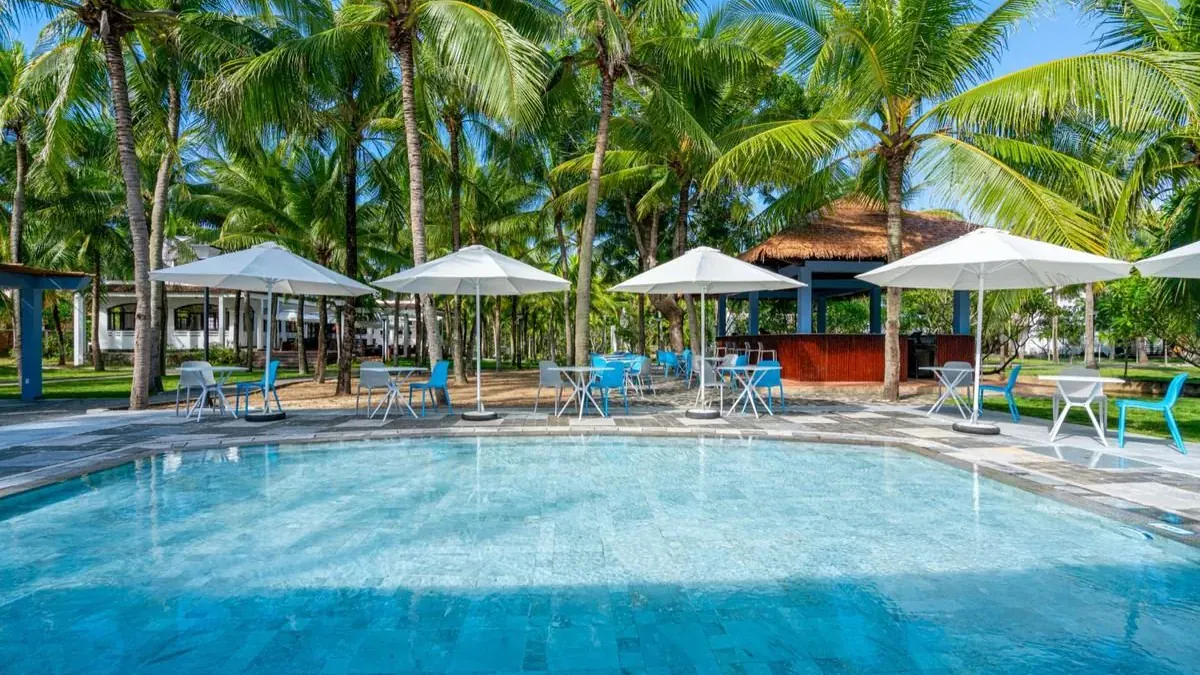 Le Belhamy's main pool with white parasols and coconut palms beyond
