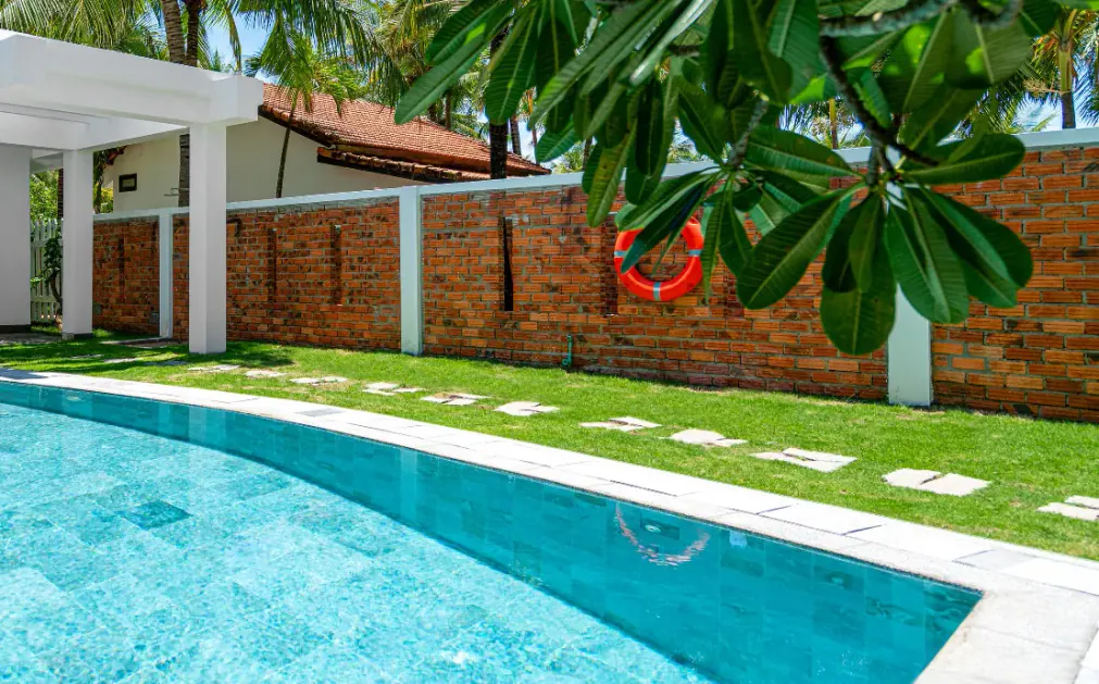 A villa's private pool, with its lawn and exposed brick wall