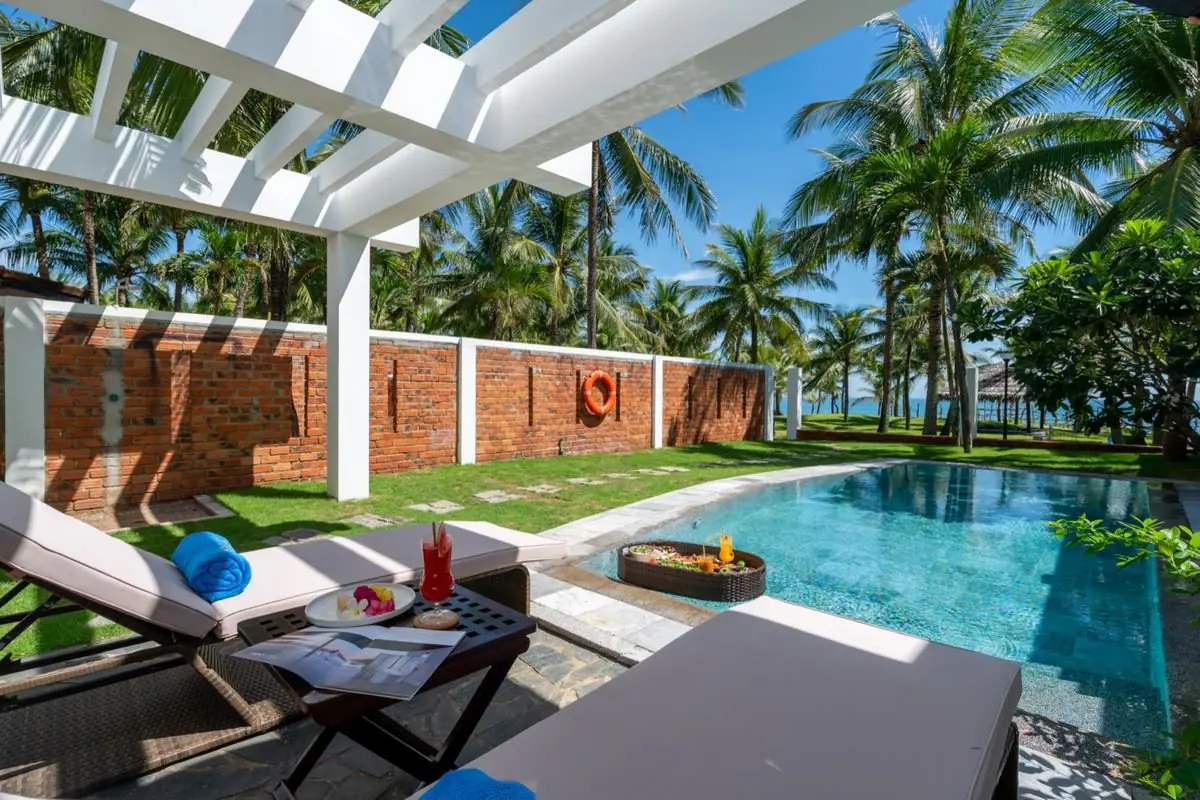 The private pool beneath the white pergola, with sun loungers and a breakfast tray floating on the water