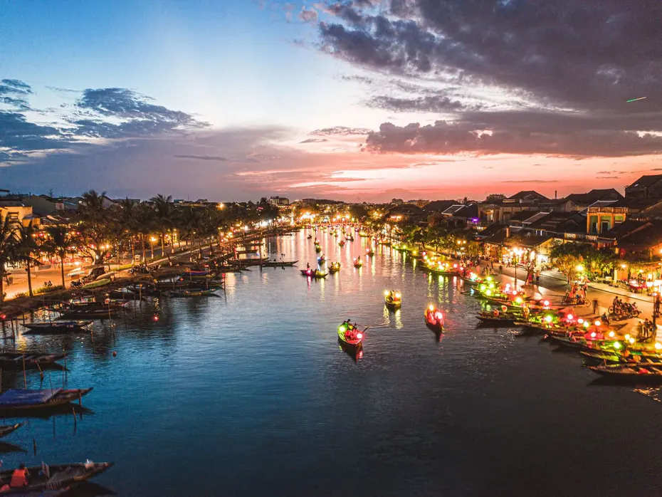 The Thu Bồn river at dusk, with lantern boats and the lit riverbank