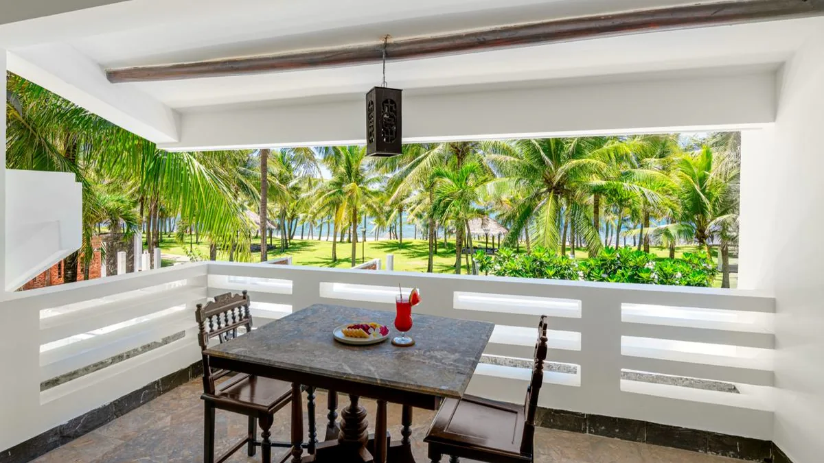 Terraza superior de una villa del Belhamy con mesa de piedra, dos sillas de madera y un farolillo encendido