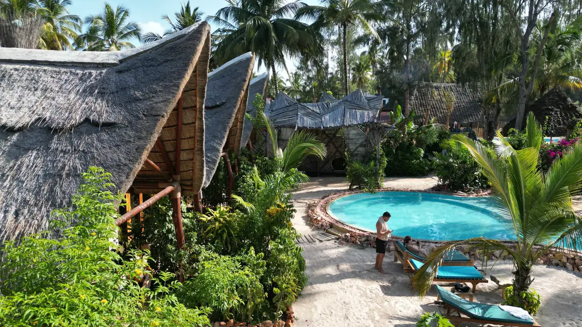 The garden at The Nest from above: makuti bungalows in the foreground and the pool behind