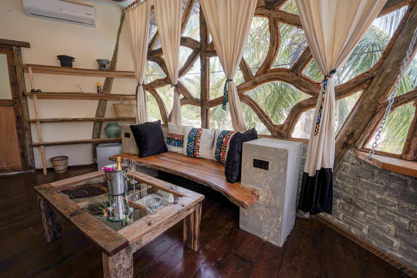 Salón de una villa de The Nest con banco corrido de madera curva y cojines de tela africana