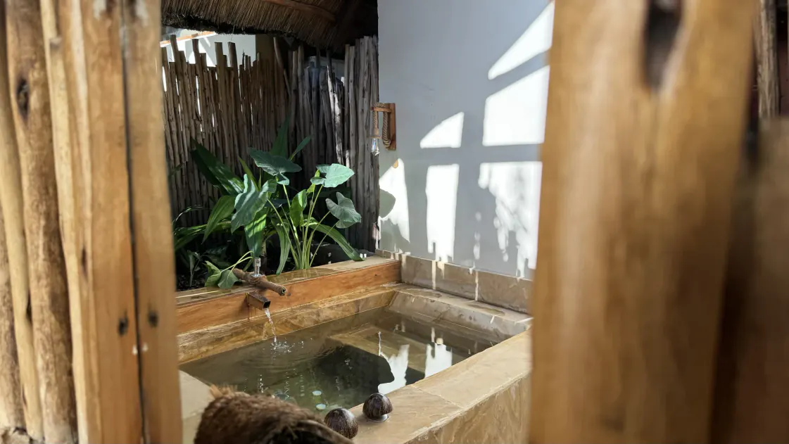 La bañera exterior de piedra de una villa del Nest, llenándose desde un caño de madera