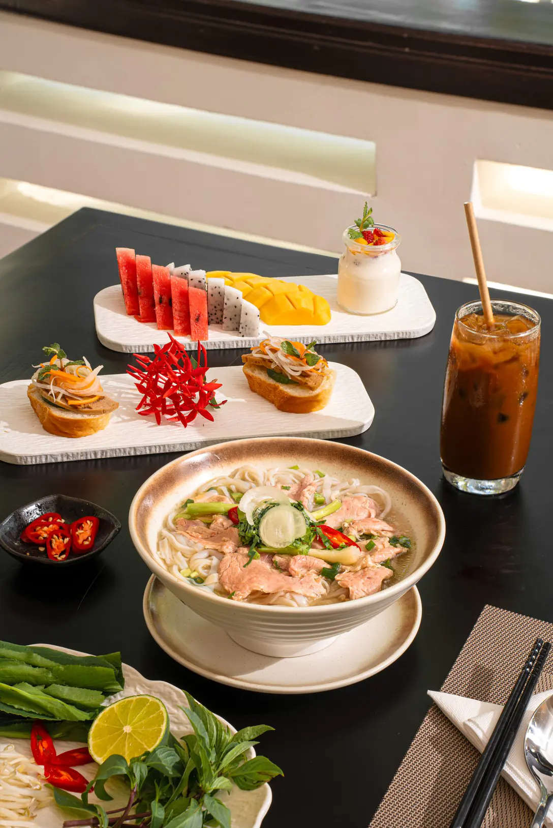 Desayuno vietnamita servido en el Belhamy: un bol de phở de ternera y una tabla de fruta cortada