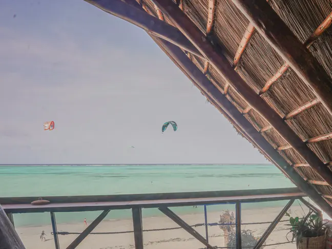 Dos cometas de kitesurf sobre la laguna de Paje, vistas desde una terraza de makuti de The Nest