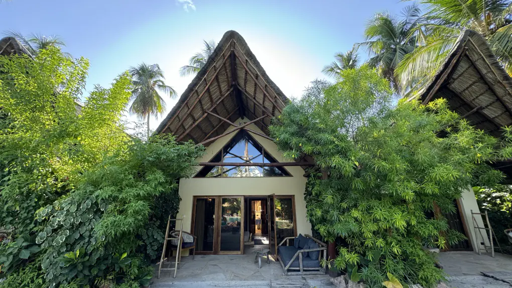 Fachada de una villa del Nest bajo techo de makuti, entre la vegetación