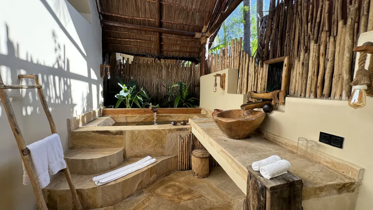 Baño exterior de la villa, con la escalera de toallas y el lavabo de tronco