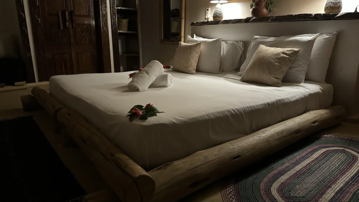 La cama king de la villa con cojines y una flor sobre la toalla plegada
