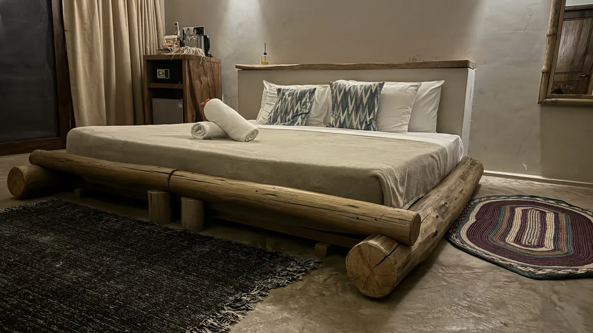 Dormitorio de la villa con la cama sobre troncos y una lámpara encendida