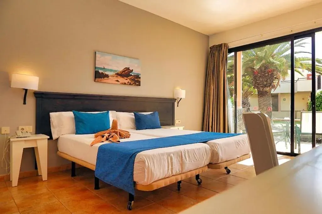 The same room from the other side: the bed with a towel folded into an elephant and the terrace behind the glass