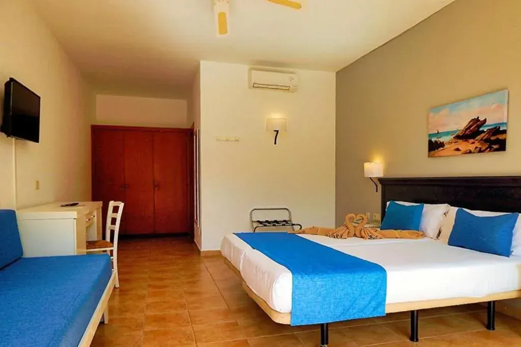 The double room from the door: a television, a mahogany wardrobe, a desk, a sofa bed and the bed beyond