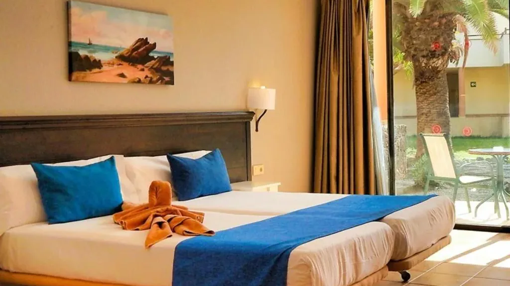 A double room at the Royal Mónica: twin beds under a dark headboard, the sliding door open onto the garden terrace
