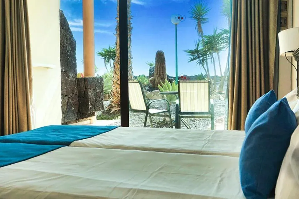 From the foot of the bed to the room terrace: two chairs and, beyond, the lava gravel and the volcanic stone wall