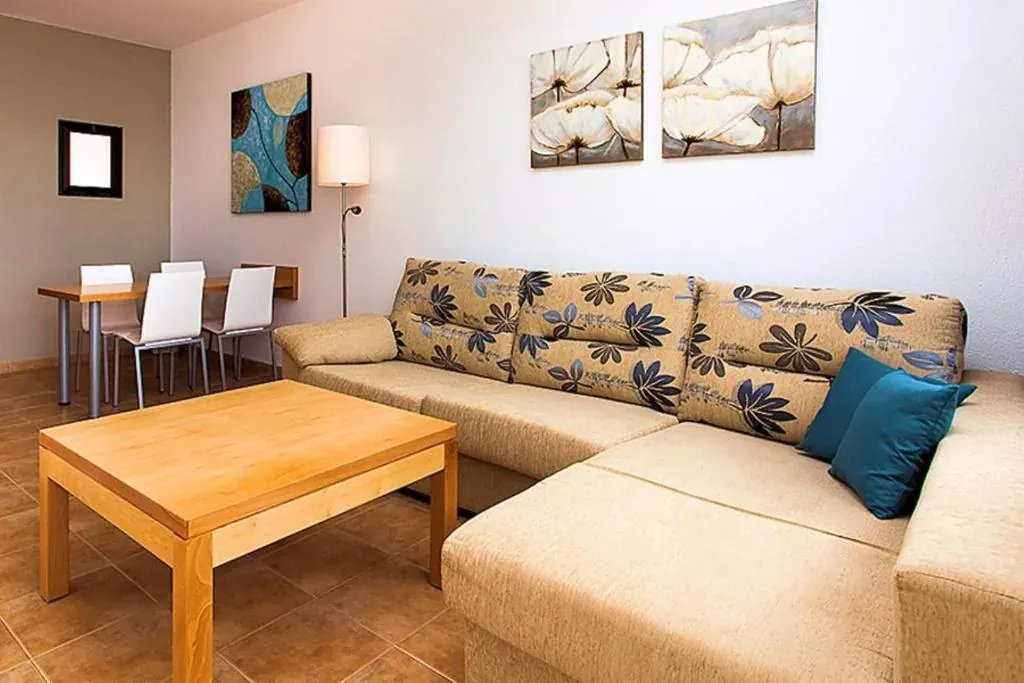 The family room living area: a patterned chaise-longue sofa, a low table and a dining set with four white chairs