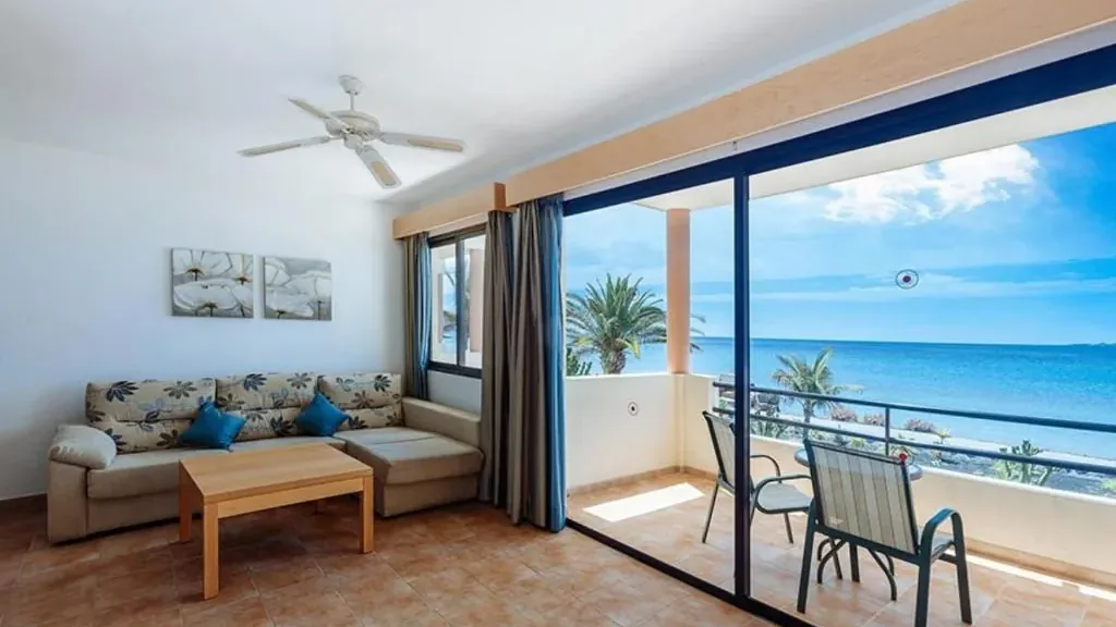 A family room living area at the Royal Mónica, the window open to the balcony and, beyond, the Atlantic and beach