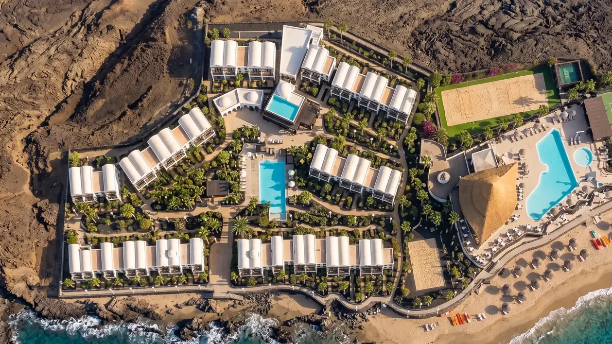Aerial view of MONEA Royal Mónica: low blocks between the lava field and the seaside pools