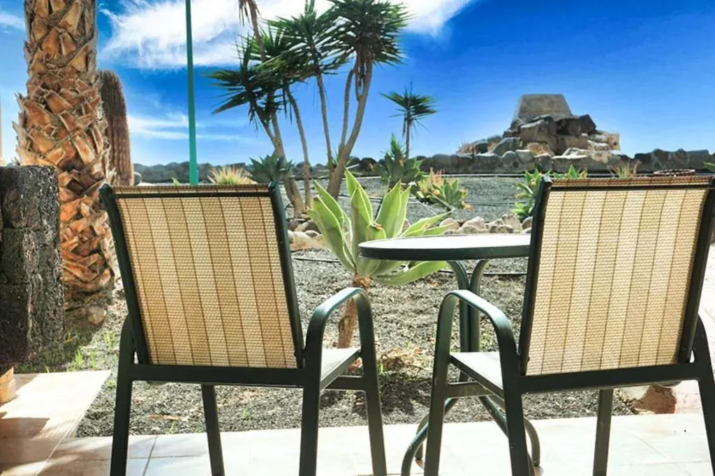 Two chairs and a round table on the terrace of a room at the Royal Mónica, facing the volcanic-gravel garden