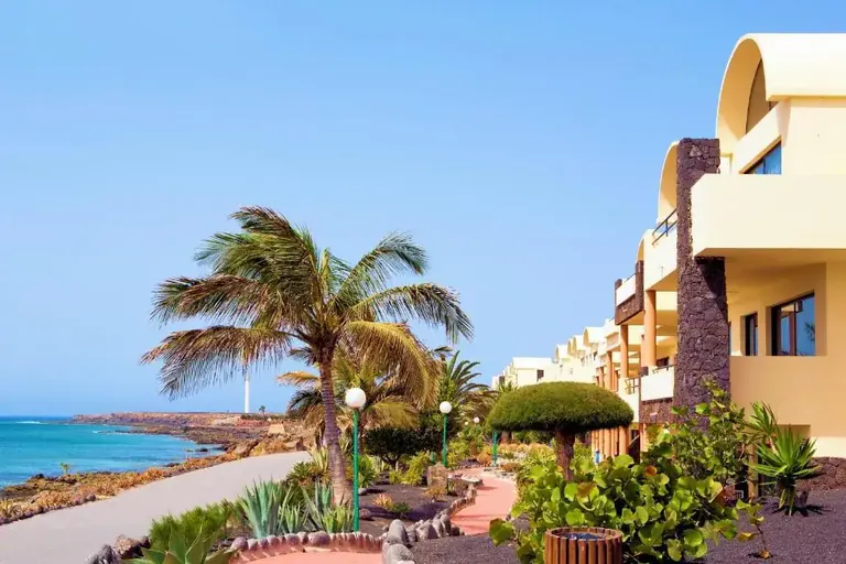 El paseo ante el Royal Mónica: fachada blanca, palmeras y el Atlántico a la izquierda